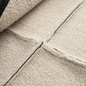Detail of cream sherpa lining with cross-stitched black seams on winter jacket