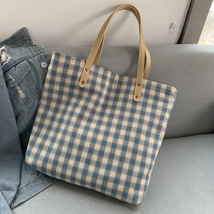 Detailansicht der blau karierten Canvas-Tasche mit Lederriemen und Goldnieten-Besatz