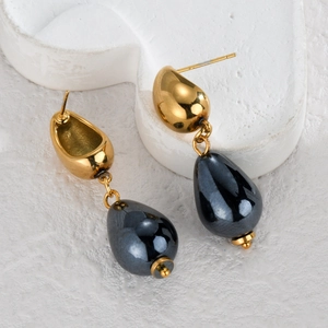 Detail of gold drop earrings with dark grey metallic beads on white heart prop