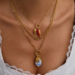 Detalle de collares en capas chapados en oro de 18K con dijes de corazón, cuerno y concha