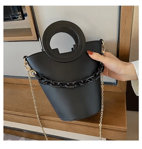 Detail of black bucket bag with circular cutout handle and chunky chain ornament