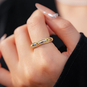 Macro detail of vintage two-tone braided ring band featuring inlaid green gemstones
