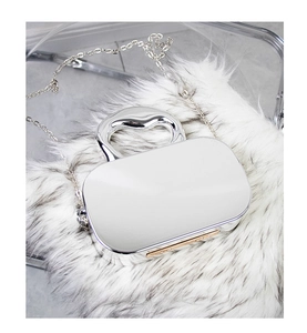 Close-up of a silver mirror-finish handbag with metal chain on white faux fur