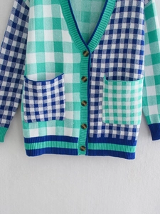 Detail of green and blue checkered knit cardigan with V-neck buttons and front pockets