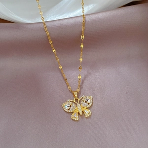 Detailed macro view of a gold butterfly pendant with clear zircon stones on silk fabric