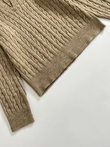 Detailed cable-knit texture and V-neckline of a khaki long-sleeve knit sweater