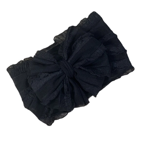 Macro view of black oversized mesh bow headband with delicate lace ruffle edges