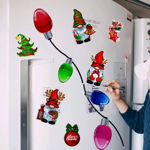 Close-up of Christmas gnome magnets and colorful bulb decals on a white refrigerator surface