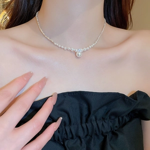 Detailed view of zircon and pearl pendant on a silver-beaded necklace for women