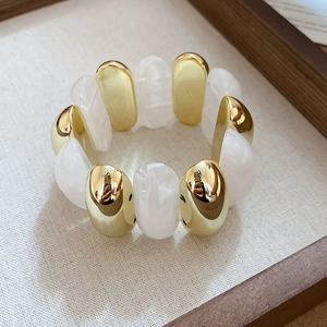 Detail of acrylic marble texture resin beads and gold-plated metal beads on elastic bracelet