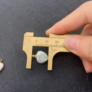 Macro view of a 13mm heart-shaped freshwater pearl pendant measured with a brass caliper
