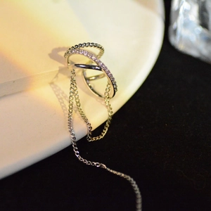 Silver double layer ear cuff with long tassel chains and zircon accents on a white plate