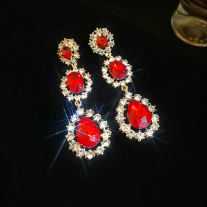 Detailed view of red crystal teardrop earrings with gold plating and sparkling rhinestones