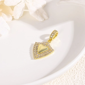 Close-up of a gold heart shield pendant with crystals on an elegant white ceramic tray
