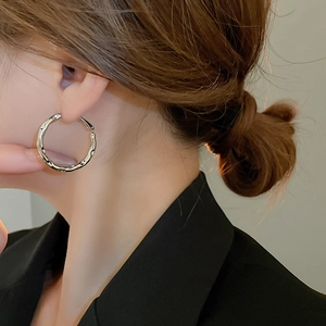 Close-up of silver irregular lava texture hoop earrings on model in minimalist style