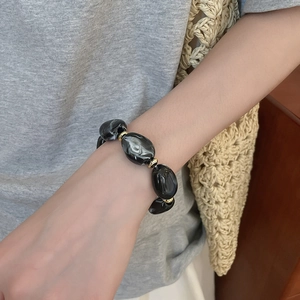 Detail of irregular marble-textured acrylic beads on a bracelet with gold metal spacers