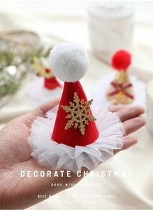Détail d'une mini pince à cheveux bonnet de Noël rouge avec flocons dorés et tulle blanc