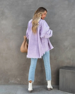 Detail view of frayed tassels and distressed seams on light purple oversized denim jacket