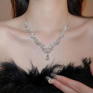 Close-up of a silver rhinestone flower necklace with a water drop pendant on a model