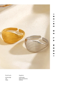 Close-up of gold and silver wavy textured open rings on soft silk fabric
