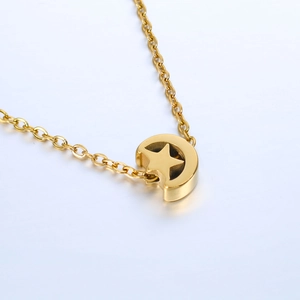 Close-up of a polished gold celestial star and moon pendant charm on a delicate chain