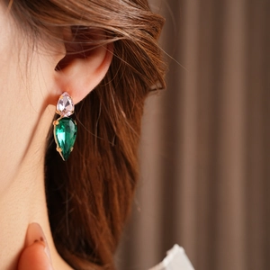 Detail of model wearing gold drop earrings with pink and green zircon crystals