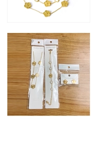 Detail of gold flower necklace and bracelet set in packaging on wooden surface