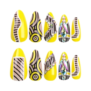Almond-shaped yellow press-on nails with abstract geometric patterns and sparkling rhinestones