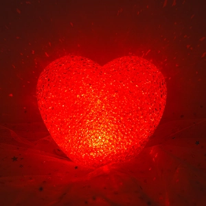 Red heart-shaped LED night light with textured surface on starry sequin fabric