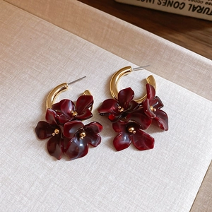 Detail of vintage burgundy resin flower stud earrings with gold circular metal base