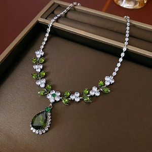 Detail of silver leaf necklace featuring green zircon teardrop and floral crystal accents