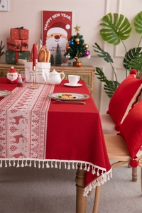 Close-up of red and white Christmas tablecloth with reindeer pattern and tassels