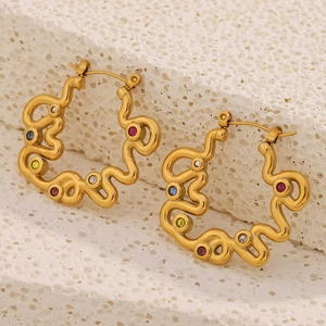 Macro view of gold-plated wavy hoop earrings featuring colorful inlaid gemstones