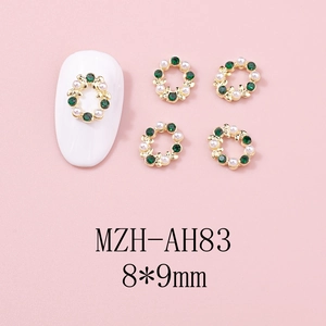 Détail macro du bijou d'ongle couronne de Noël avec gemmes vertes et perles blanches