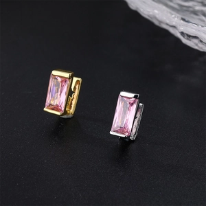 Close-up of elegant gold and silver earrings with rectangular pink crystal stones