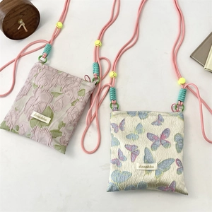 Detail of floral and butterfly jacquard fabric with adjustable woven strap on small bag