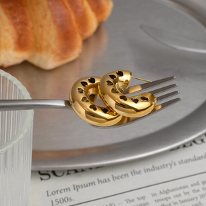 Detail of gold-plated stainless steel C-shaped hoop earrings with heart cutouts