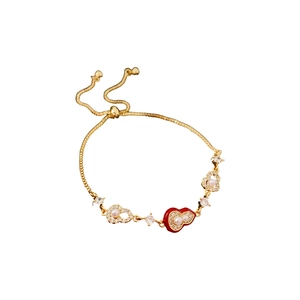Gold-plated calabash bracelet with pearls and red zircon heart on white background