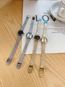 Close-up of elegant square dial metal watches in silver and gold on a cafe table