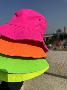 Stack of four vibrant fluorescent neon bucket hats in pink orange green and yellow colors