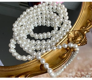 Detailed view of luxury long pearl necklace elegantly layered on a gold vintage mirror