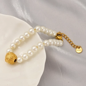 Minimalist pearl bracelet with gold textured beads on white ceramic tray