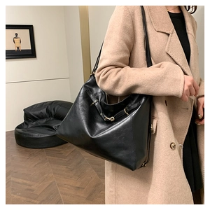 Detail view of high-capacity black leather tote with grainy texture and golden buckle