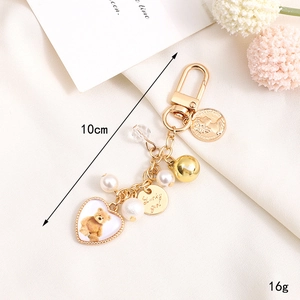 Golden keychain with pearl charm and heart bear pendant on a textured white background