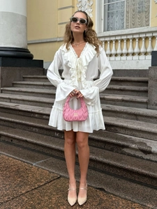 Detail of white V-neck chiffon dress with elegant ruffle sleeves and feminine styling