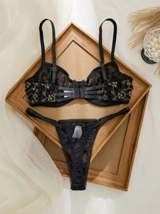 Détail d'un ensemble de lingerie en dentelle noire de luxe avec broderie florale dorée