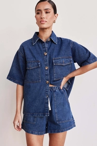Close-up of deep blue denim texture and stitching on women's shirt and shorts set
