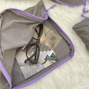 Detail of grey travel storage bag with purple zipper showing nylon texture and spacious interior