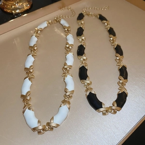 Détail de colliers émaillés noir et blanc sur plateau doré avec design vintage croisé