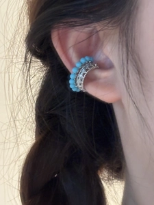 Gros plan sur un earcuff double couche avec perles turquoise et motif vagues en argent